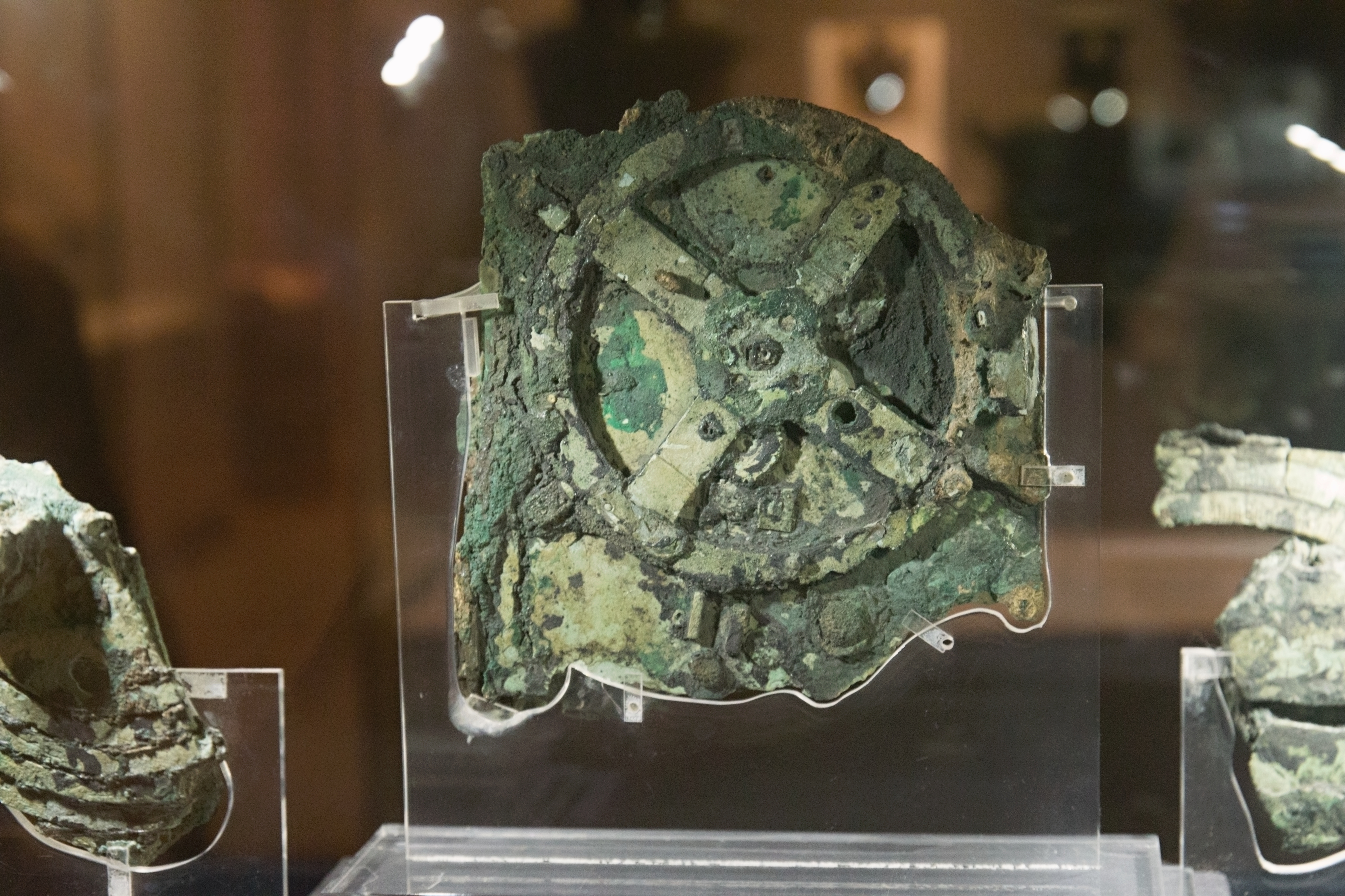 Side view of Antikythera mechanism fragment showing layered bronze plates and corrosion.